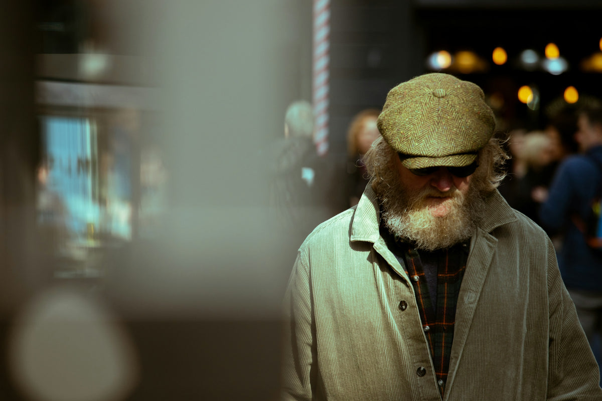 Man in a herringbone flat cap and corduroy coat on a city street